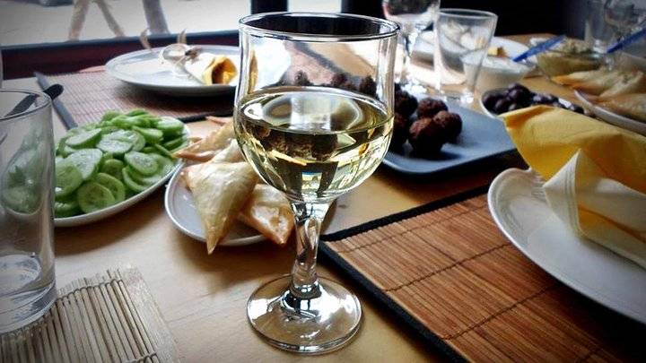 Ποτήρι λευκού κρασιού και πιάτα με ελληνικούς μεζέδες σε τραπέζι